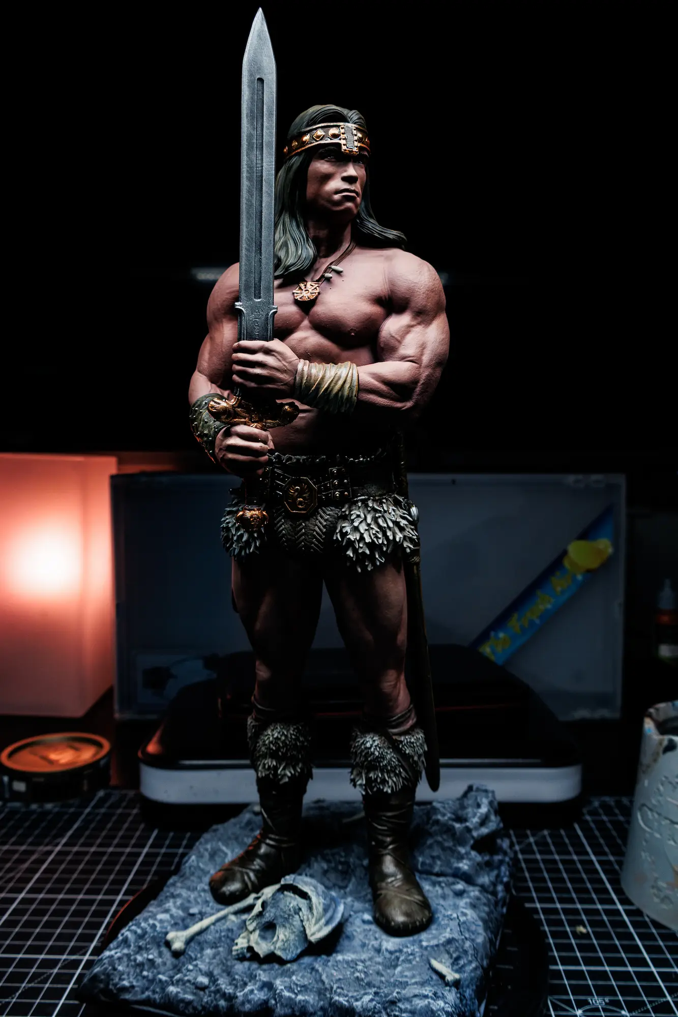 Painted resin miniature of Conan the Barbarian holding a sword, with shaded skin, leather straps and a stone terrain base.
